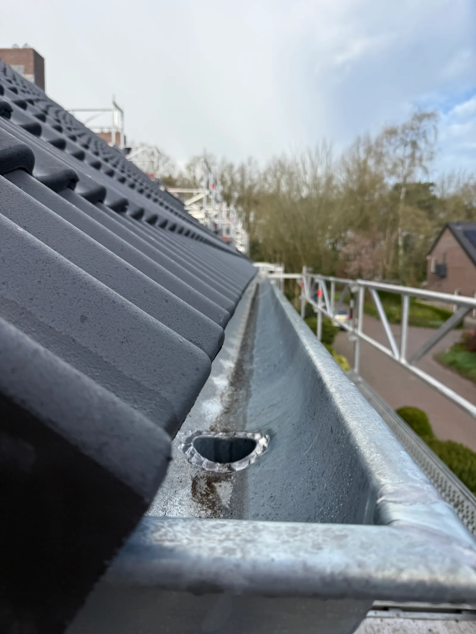 De nieuwe zinken goot met uitloop naar de regenpijp